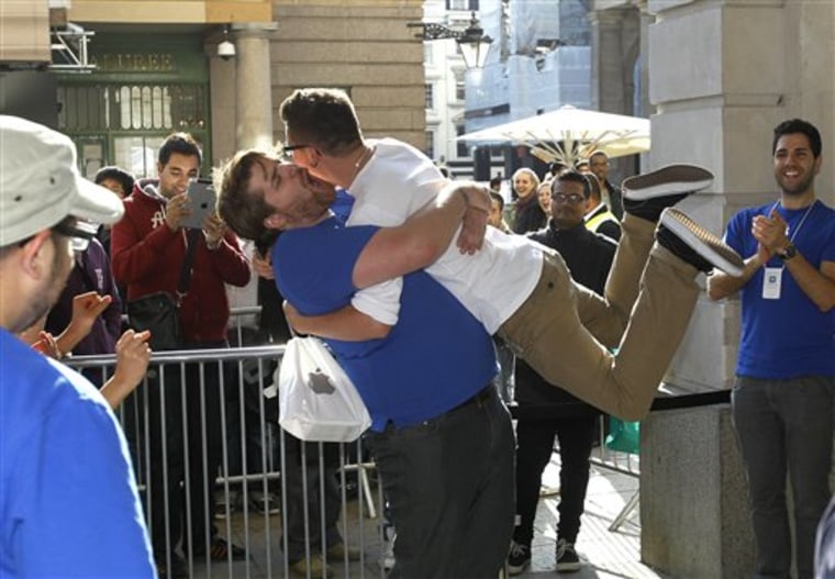 A customer jumps into the arms of an Apple employee outside the Apple Store in Covent Garden, to celebrate his purchase of the new iPhone 4S, which went on sale in London,  Friday, Oct. 14, 2011. (AP Photo/Kirsty Wigglesworth)
